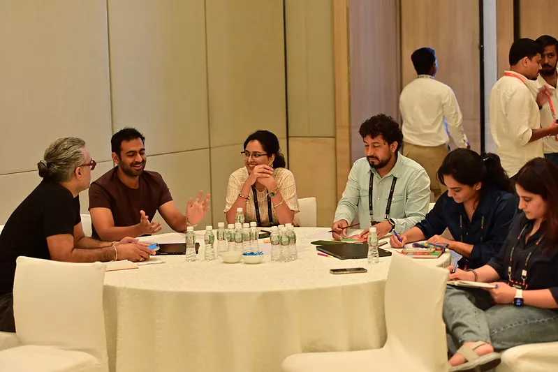 UX practitioners collaborating around a round table during a workshop session